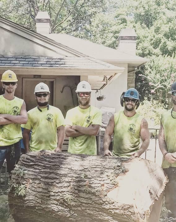 five male arborists in Broken Arrow, OK standing in front of a piece of large tree trunk